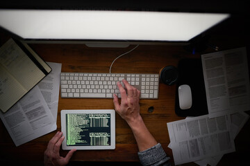 Binary is his second language. High angle shot of an unidentifiable computer programmer working alone late at night.