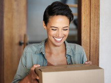 Right On Time. Shot Of A Smiling Young Woman Standing At Her Front Door Receiving A Package From A Courier.