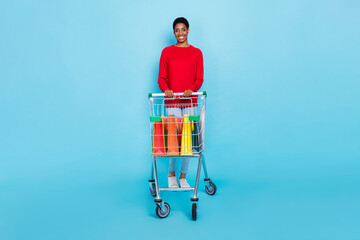 Full size photo of good mood nonbinary man go shopping buy present for family isolated on blue color background