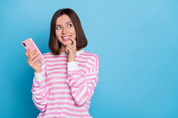 Poster - Photo of impressed millennial brunette lady hold telephone look promo wear striped pullover isolated on blue background