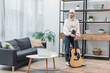 © LIGHTFIELD STUDIOS - full length view of arabian woman standing with acoustic guitar in modern living room.