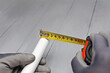 the plumber measures the length of a plastic pipe with a tape measure