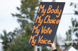 A hand holding a sign supporting pro-choice abortion laws during a planned parenthood rally for abortion justice.
