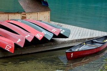 A Canoe In The Water Is Ready To Rent While Other Canoes Are Stored On The Dock