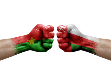 Two hands punch to each others on white background. Country flags painted fists, conflict crisis concept between burkina faso and oman