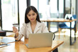 © bongkarn - Businesswoman holding a credit card and using laptop computer.