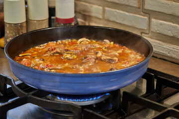 Sticker - Veal tongue with tomato sauce, mushrooms and capers is fried in frying pan on gas stove. French gourmet cuisine