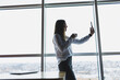 © DSMT - Young businesswoman wearing glasses and holding a phone. In an office or business center against the background of large windows of a skyscraper. Work and career, concept
