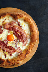 Wall Mural - Carbonara pizza with bacon and egg on dark stone background