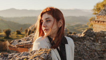 Beautiful girl with white dress explores an ancient Italian castle at sunset