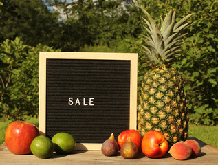 Wall Mural - Fresh Pineapple outdoors with Apricots, Peaches and figs. sale sign garden in background