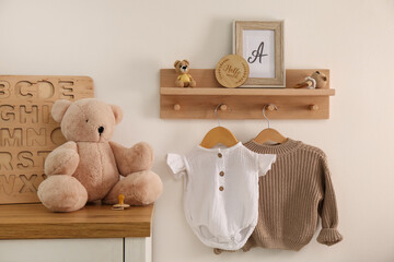 Poster - wooden shelf with baby clothes, toys and furniture in room. interior design