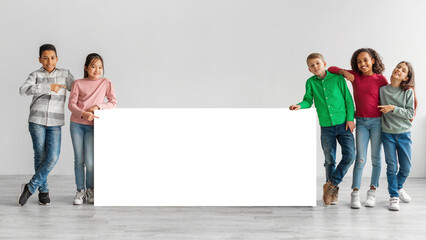 Wall Mural - Happy Diverse Kids Standing Near White Board Over Gray Background
