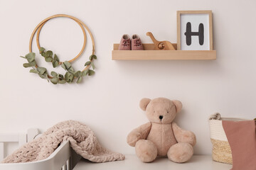 Poster - Wooden shelf with baby accessories and toys in child room. Interior design