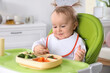 © New Africa - Cute little baby eating food in high chair at home