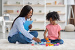 © Prostock-studio - Happy black girl and child development specialist playing with bricks