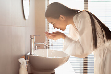 Wall Mural - Young chinese woman in silk bathrobe washing face in bathroom