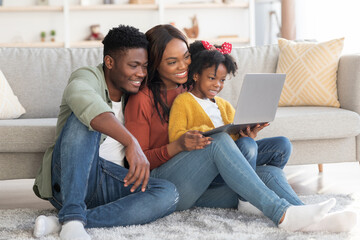 Wall Mural - Happy african american family of three relaxing with laptop at home