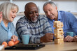 © Prostock-studio - Closeup of multiracial senior people playing jenga at home