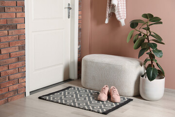 Poster - Hallway interior with beautiful houseplant, soft ottoman and door mat on floor near entrance