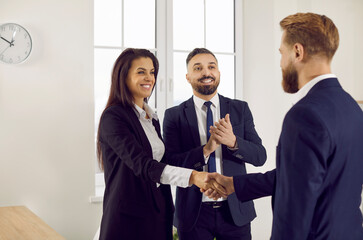 Wall Mural - Happy people meeting in the office, making a profitable deal and exchanging handshakes. Team of smiling successful business partners confirming collaboration and shaking hands