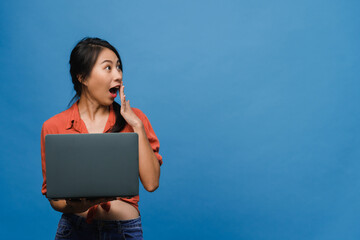 Wall Mural - Young Asia lady using laptop with positive expression, smiles broadly, dressed in casual clothing feeling happiness and stand isolated on blue background. Happy adorable glad woman rejoices success.