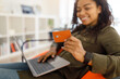 © Prostock-studio - Happy woman holding debit credit card, using pc