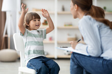 Happy Emotional Little Boy Talking To Therapist At Office, Sharing Funny Story To Specialist During Session