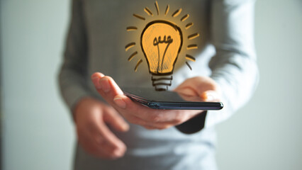 Wall Mural - man holding and using a digital device and bulb hologram