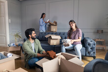 Man And Woman Moving Out While Their Friend Helping Them Pack Everything In Cardboard Boxes.