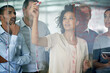 © Tabitha Rose/peopleimages.com - Shes got their undivided attention. Shot of a group of creative businesspeople plotting out details on a glass wall.