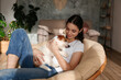Portrait of young beautiful woman lying on a papasan chair with her adorable wire haired Jack Russel terrier puppy. Loving girl with rough coated pup on saucer chair. Background, close up, copy space.
