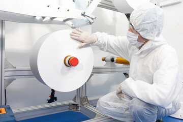 Wall Mural - male engineers wearing personal protective equipment uniform(PPE) and checking production line for quality control from non woven material on automatic machine