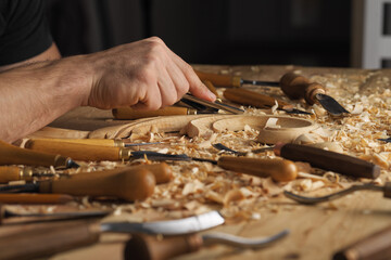 Wall Mural - Wood carving, master's hands work with a wooden surface, a professional does wood crafts