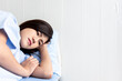© Anatta_Tan - Asian woman patients, is sad and lying in patient's bed with alone, On white wall  background, to people health care and health insurance concept.