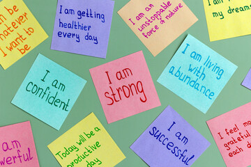 Positive affirmations concept. Phrases of different colors sheets for notes on a green background. Motivational concept with handwritten text.