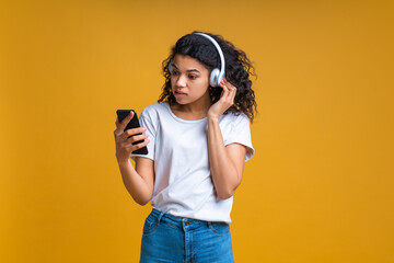 Wall Mural - Girl concentrated on setting her wireless headphones and browsing music mobile application on her smartphone choosing a song