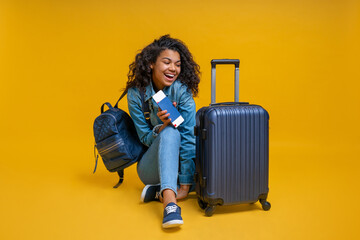 Wall Mural - Beautiful excited girl turist sitting on the floor with passport and boarding pass in hands, smiling and looking at her suitcase