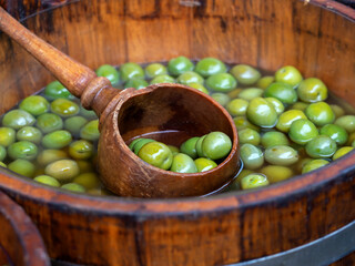 Wooden barrel of green olives with ladle at a Food Market 