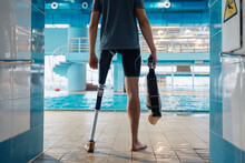 Rear View Of Athlete With Artificial Leg In Front Of Indoor Swimming Pool.