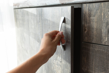 Person opens the door in the closet, women's hand, close-up