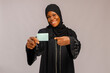 © Vic Josh - muslim woman holding credit card and smiling at camera isolated on grey