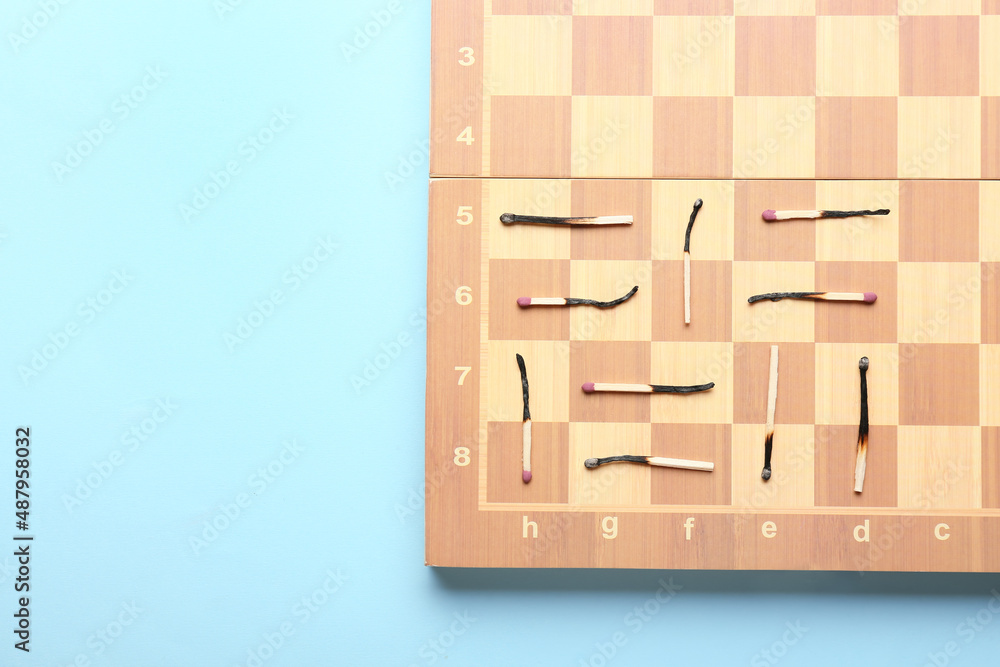 Chess board with burnt matches on color background. Concept of burnout