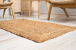 Wicker rug on light wooden floor in room interior, closeup