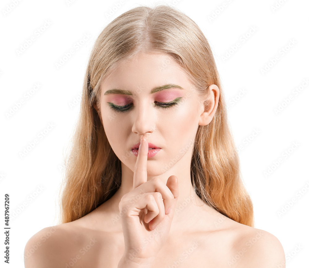 Beautiful girl with unusual eyebrows showing silence gesture on white background
