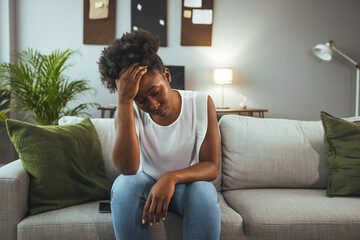 Young attractive African American woman lying at home living room couch feeling sad tired and worried suffering depression in mental health, problems and broken heart concept.