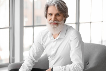 Poster - Portrait of handsome mature bearded man sitting in armchair at home