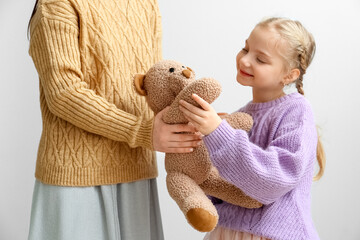 Sticker - Little girl with toy and her mother in warm sweaters on light background