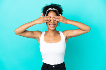 Sticker - Young latin woman isolated on blue background covering eyes by hands and smiling