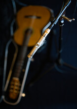 A Condenser Microphone Mounted On A Rack Against The Background Of A Guitar Lying In An Open Trunk On A Dark Blue Background
